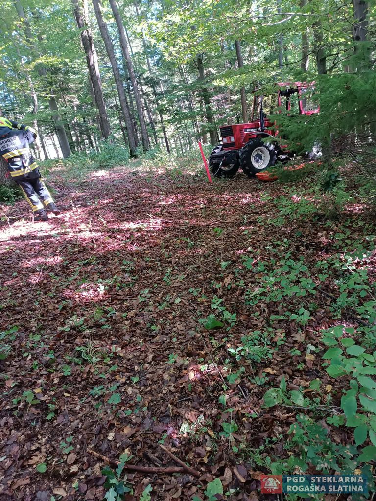 Traktor in gasilska oprema na tekmovalnem mestu v gozdu.