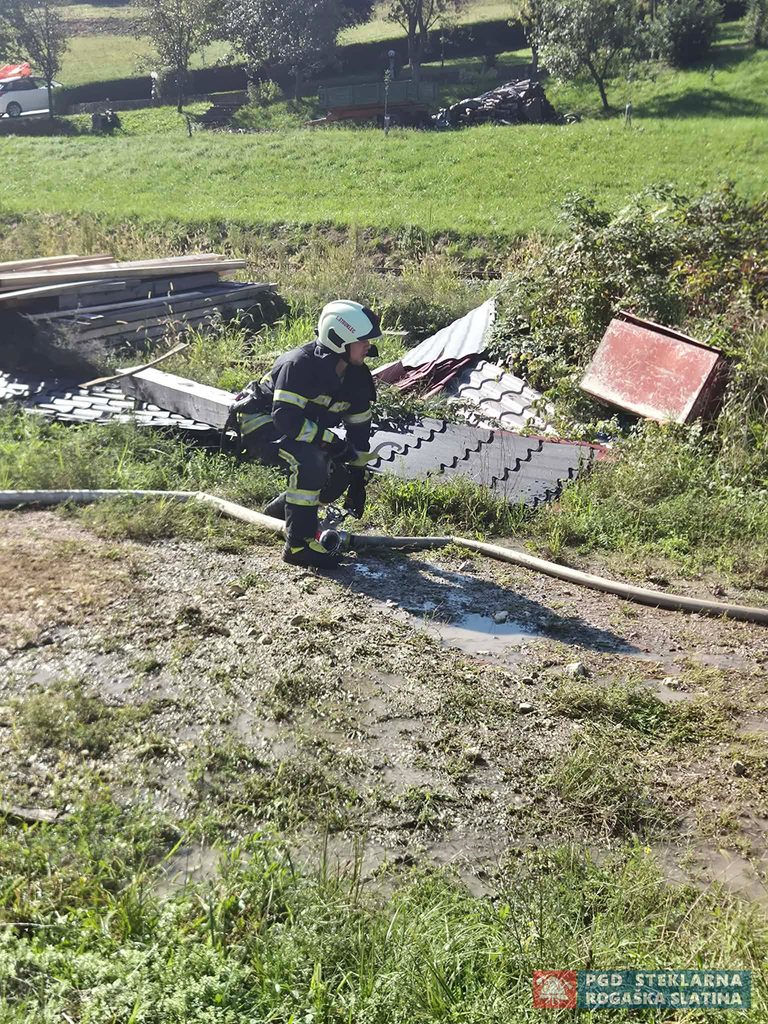 Gasilec s cevjo in ročnikom na travnatem terenu med tekmovalno vajo.
